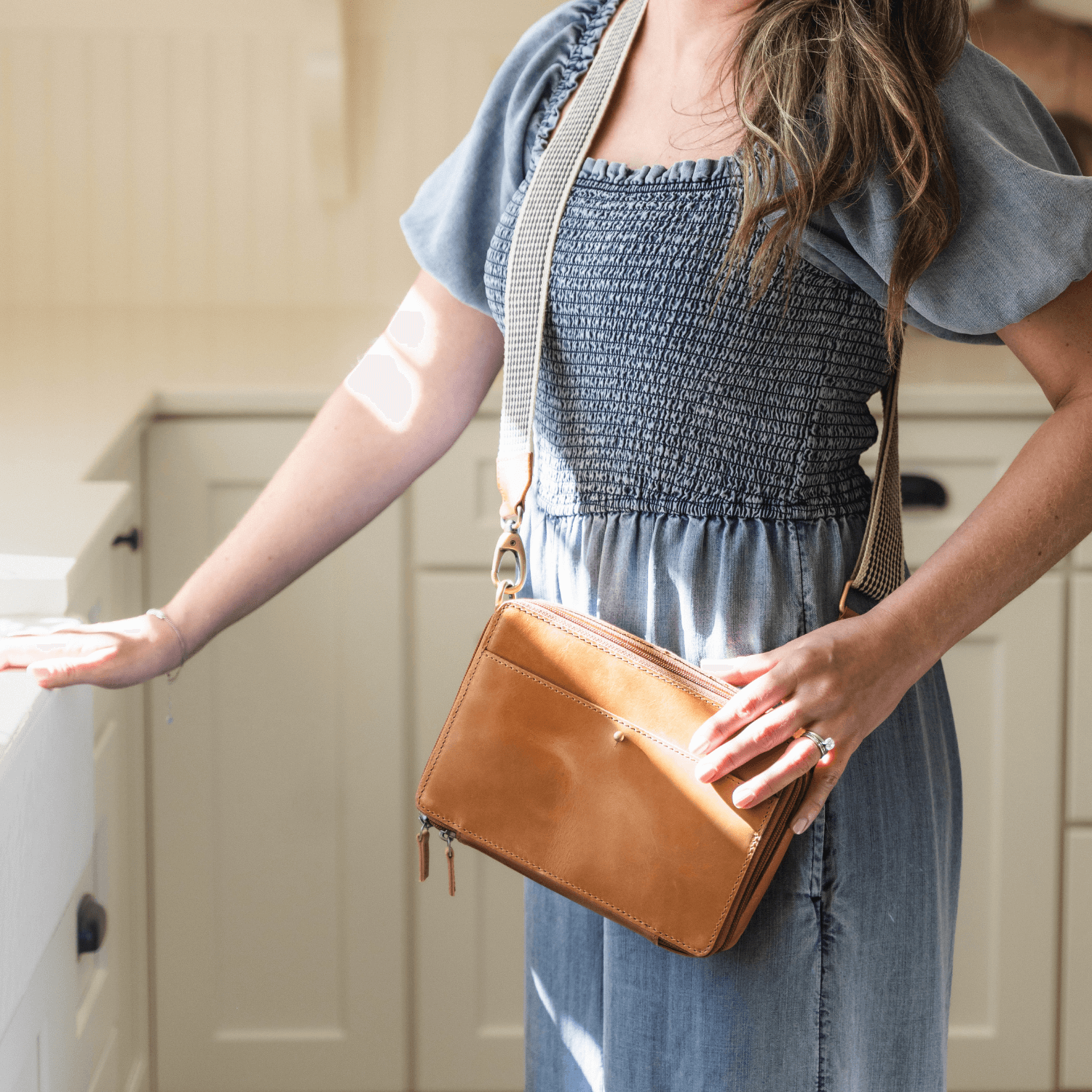 Woman standing in kitchen with Nomad crossbody