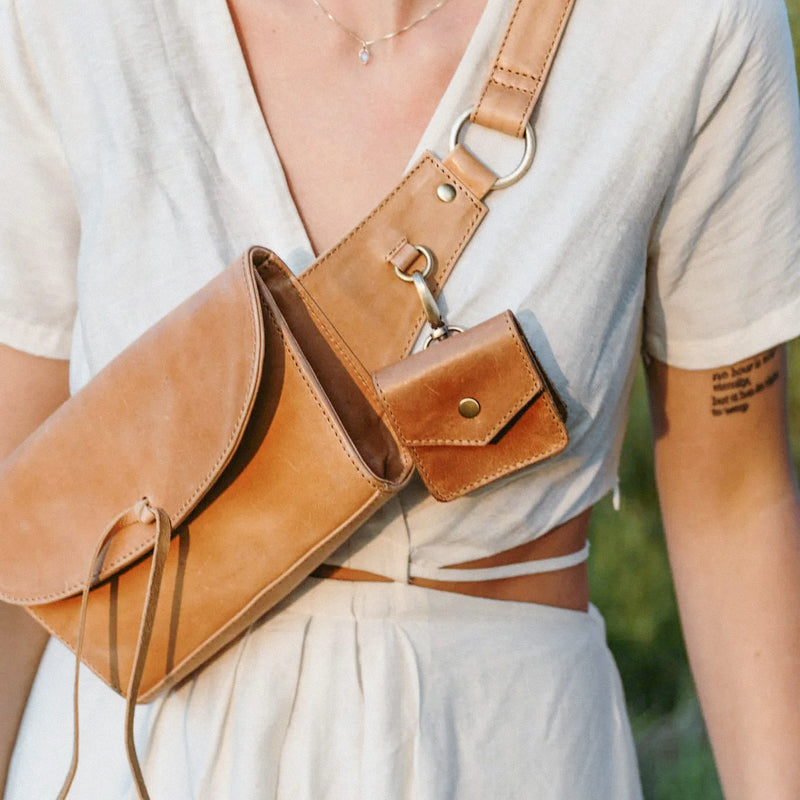 Woman in white outfit wearing crossbody with Airpod case from Elevate attached