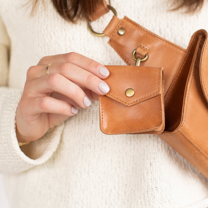 Woman showing Airpod Case from Elevate attached to purse