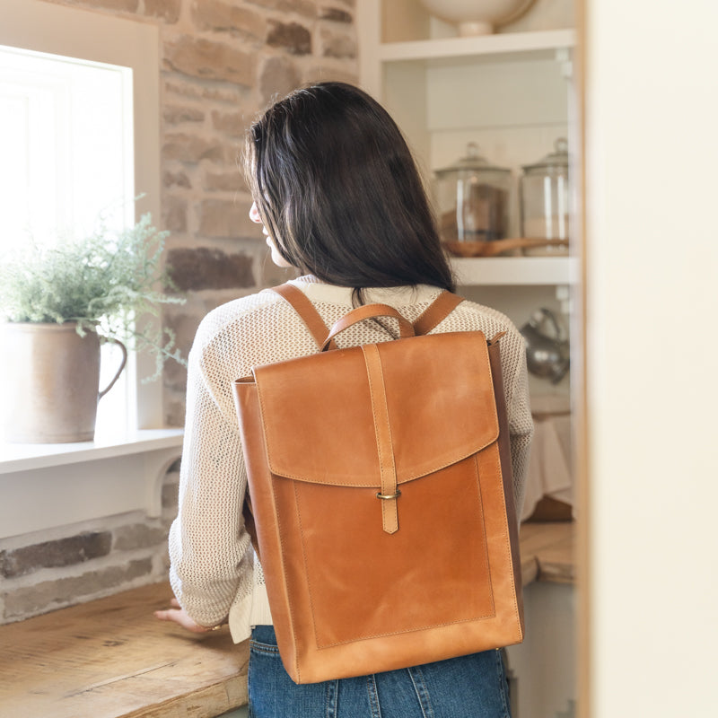 Woman wearing the Atlas leather backpack from Elevate inside her house