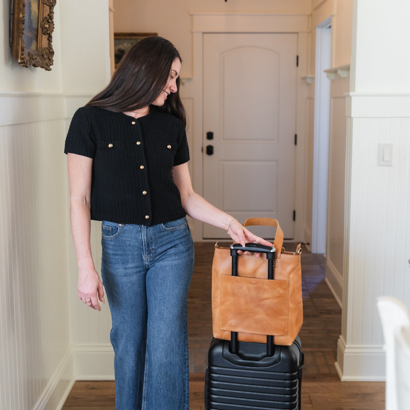 Woman holding luggage with Elevate bucket tote on top